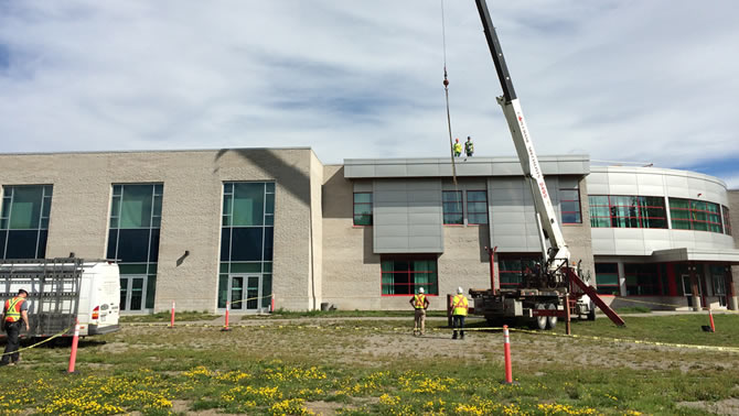 A crane installs 25 solar panels at UNBC.