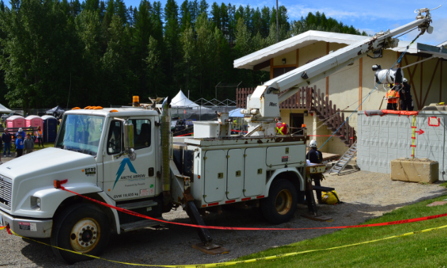 A large truck with a crane lifts a barrel shaped like a cow