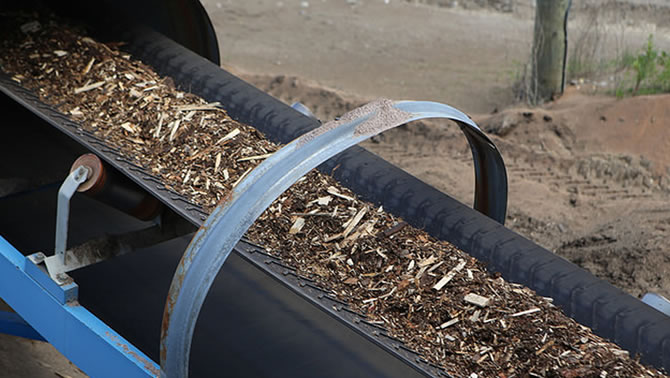 Picture of hog fuel on a conveyor belt.