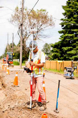 A man surveying in the middle of a road on the Fort William First Nation housing project. 