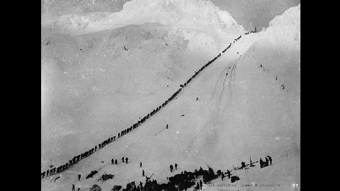 Miners ascending the steep, snowy summit of Chilkoot Pass.