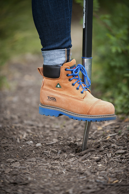 A close up of a boot stepping on a shovel. 