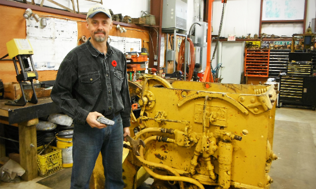 Brian Mills poses with Galena silver-lead-zinc and an Eimco mucking machine, used to scoop ore into ore cars.