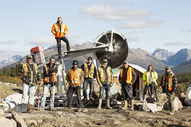 The Bunces and the crew pose next to one of their saws in the field. 