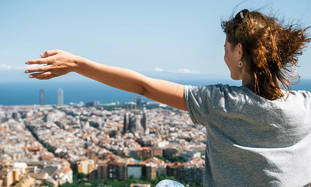Picture of girl with arms spread, cityscape in background. 