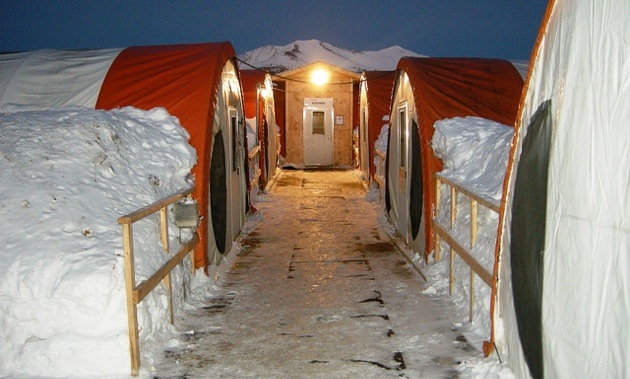 A photo of banks of snow against 4 long tents at the Selwyn Project camp.