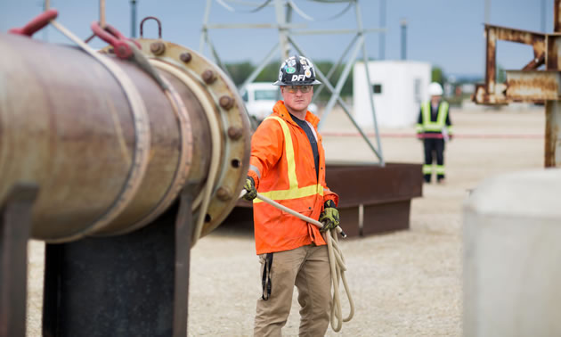 A young worker is standing by a pipeline.