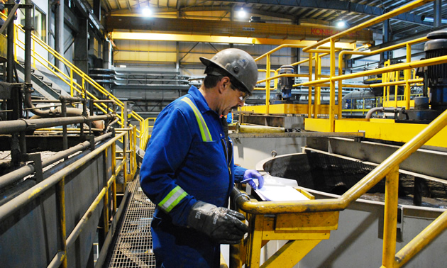 a man in coveralls and hard hat working in a mine processing plant