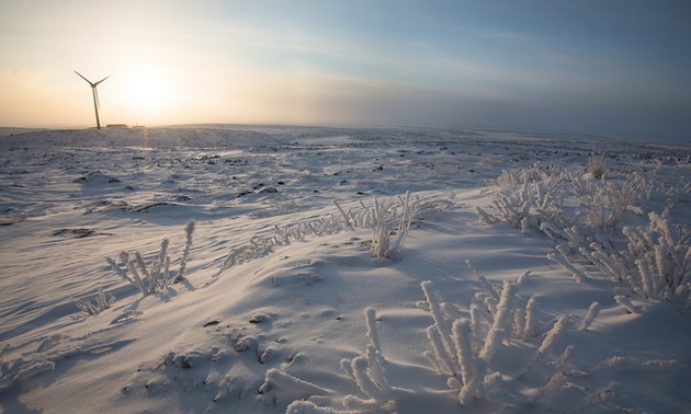 A view of one of Diavik's wind turbines, looking over a large field of snow, showing the remoteness of the location. 