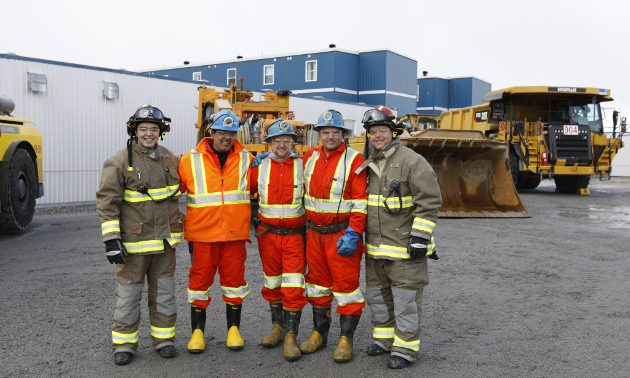 5 men posing for picture, in safety gear. 