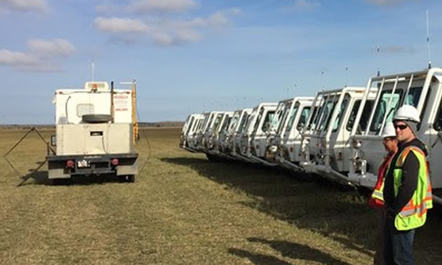 Picture of trucks lined up in field, with technicians monitoring equipment.